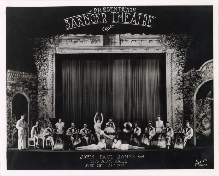 A black and white image of the cast and band/orchestra of a 1933 live performance at the Saenger Theatre, posing in front of the drawn curtain.