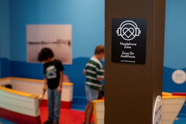 PCM Headphone Zone sign in the foreground with children playing in the background
