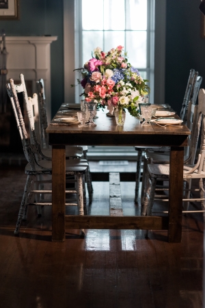 A small indoor wooden table elegantly decorated with florals and place settings for 4