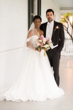 A bride and groom post on the porch of Barkley House