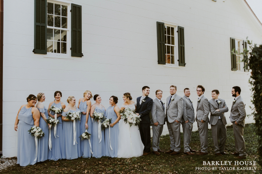 A posed outdoor shot of the bride, groom, and wedding party at the Barkley House wedding venue